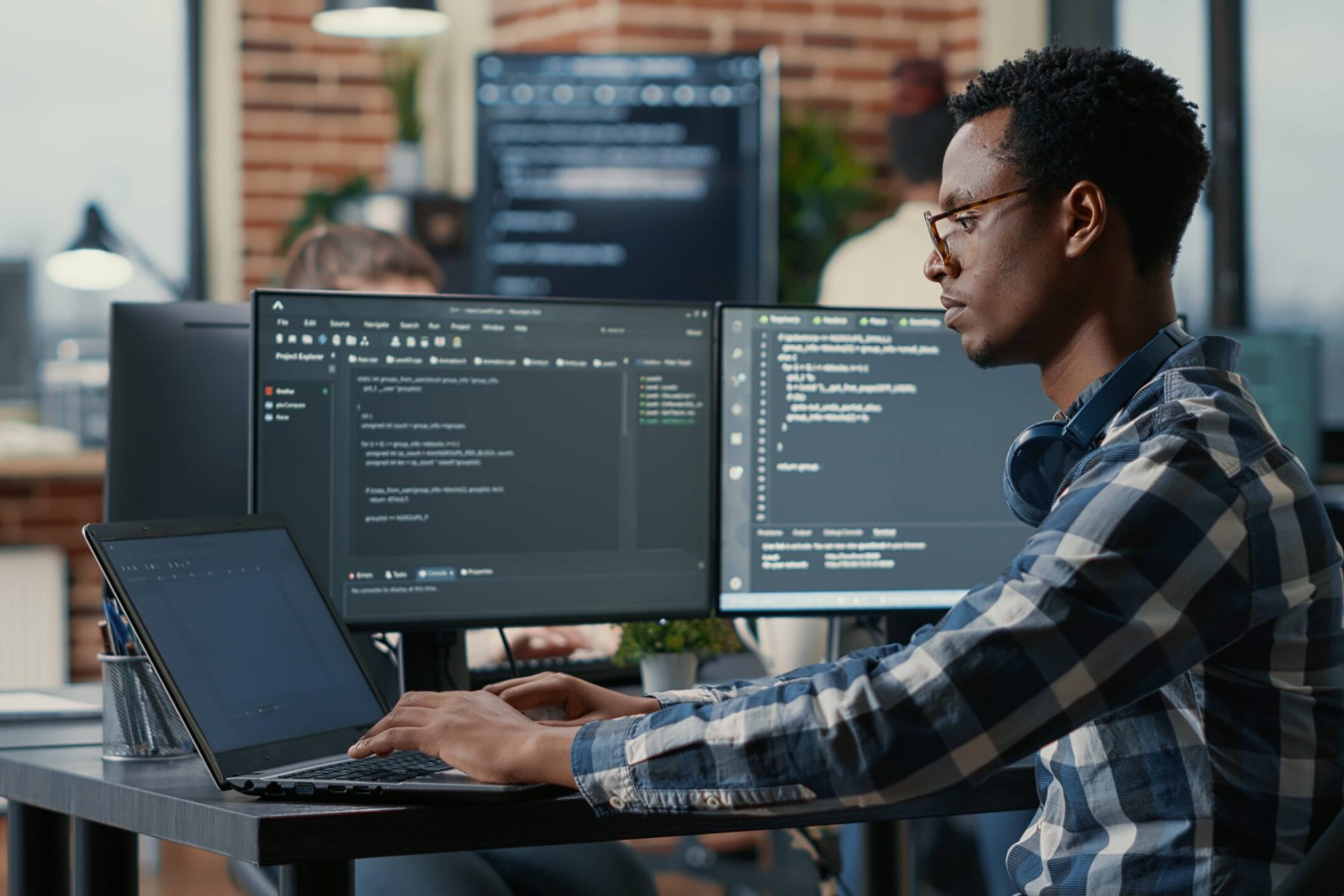 Nephsonic_portrait-african-american-developer-using-laptop-write-code-sitting-desk-with-multiple-screens-parsing-algorithm-software-agency-coder-working-user-interface-using-portable-computer
